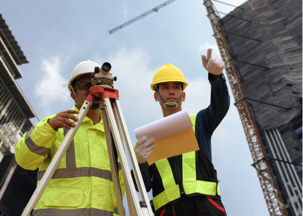 Two construction workers observe the surrounding buildings